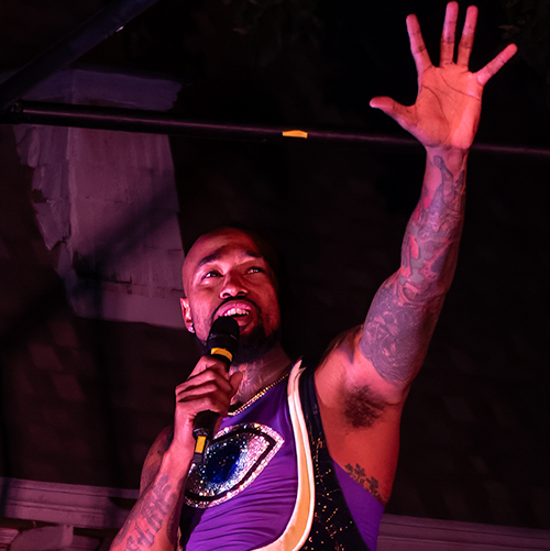 Performer gesturing with open hand and speaking into a microphone